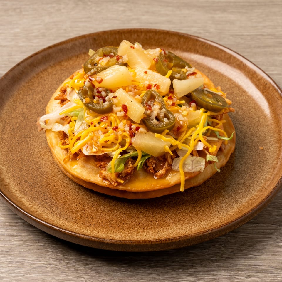 Island Taco Shack's tostada with shredded meat, cheese, lettuce, pineapple, and jalapeños.
